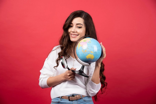 Happy woman posing with globe and magnifying glass. High quality photo