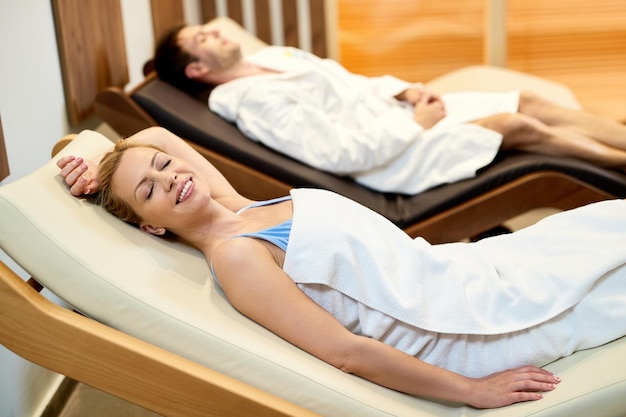 Free Photo happy woman relaxing with her husband on lounge chairs while spending a day at health spa