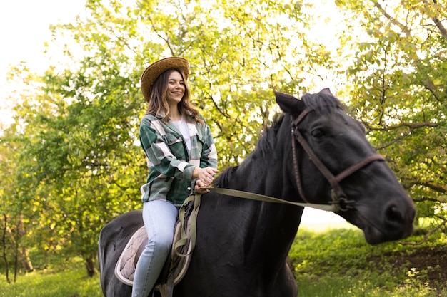 Free photo happy woman riding horse medium shot