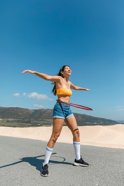 Happy woman on road turning hula hoop