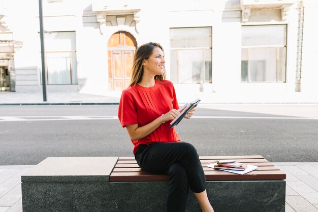 Happy woman sitting on bench with diary