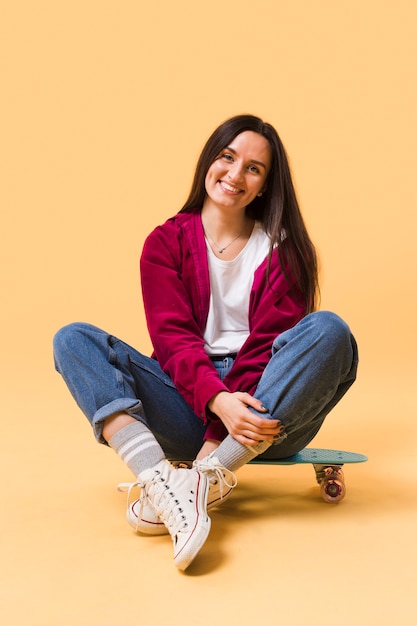 Happy woman sitting on skateboard