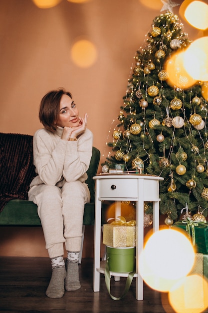 Happy woman sitting on sofa by the christmas tree