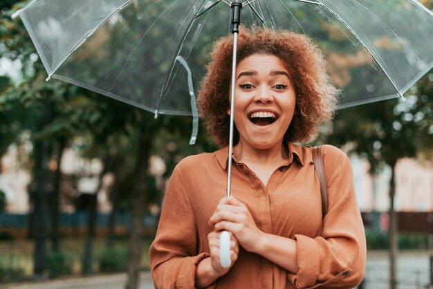 Happy woman standing under her umbrella in autumn