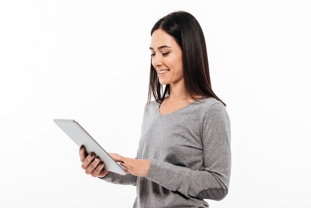 Happy woman standing isolated using tablet computer.