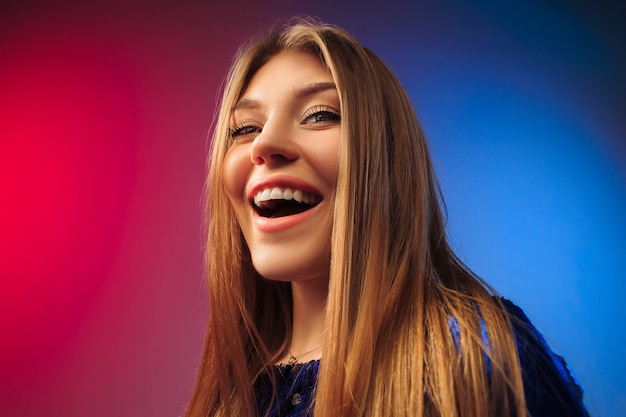 The happy woman standing and smiling against colored space.