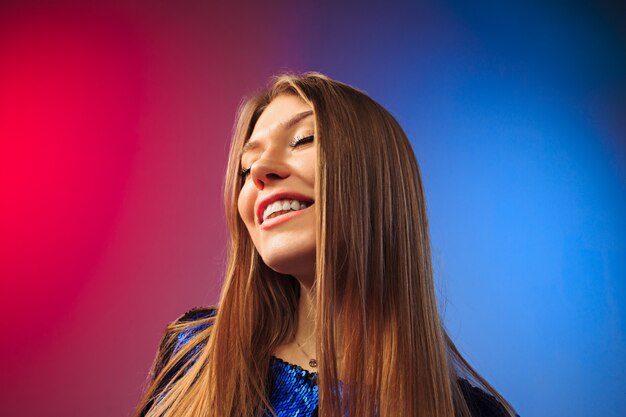 The happy woman standing and smiling against colored wall