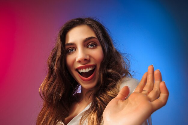 Happy woman standing, smiling on colored studio background. Beautiful female half-length portrait. Young satisfy woman. Human emotions, facial expression concept.