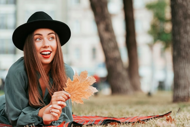 Free photo happy woman staying on a blanket in nature