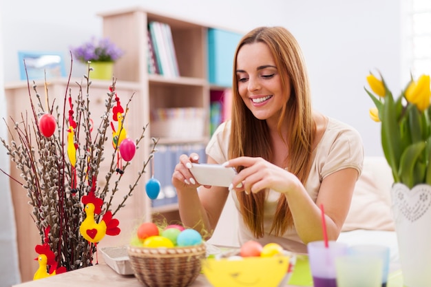 Happy woman taking photo by mobile phone in easter holiday