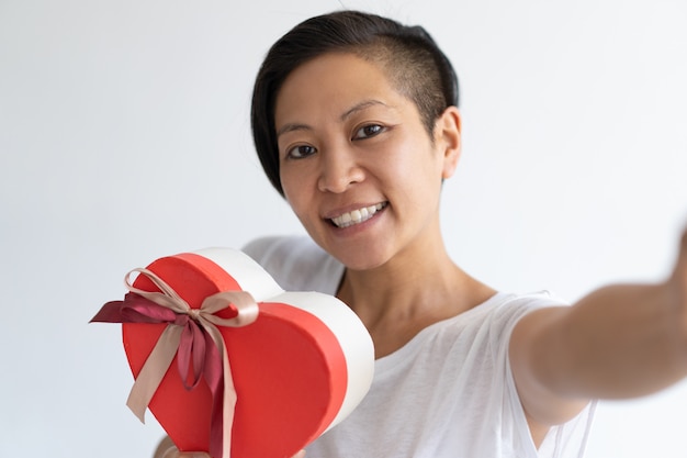 Happy woman taking selfie photo with heart shaped gift box