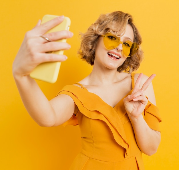 Happy woman taking a selfie while wearing sunglasses