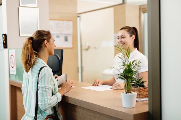 Free photo happy woman talking to a receptionist while arriving at the spa