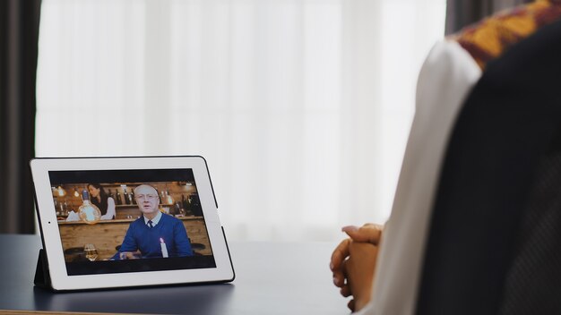 Happy woman talking with her father on a video call using tablet computer.