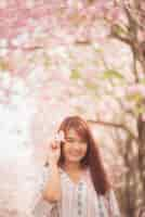 Free photo happy woman traveler relax feel free with cherry blossoms or sakura flower tree on vacation