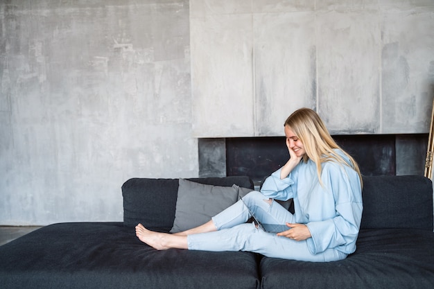 Happy woman using silver laptop while sitting on sofa