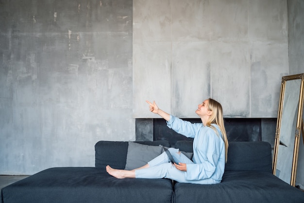 Free photo happy woman using silver laptop while sitting on sofa