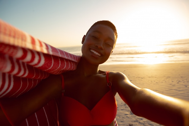 Happy woman with blanket standing on the beach