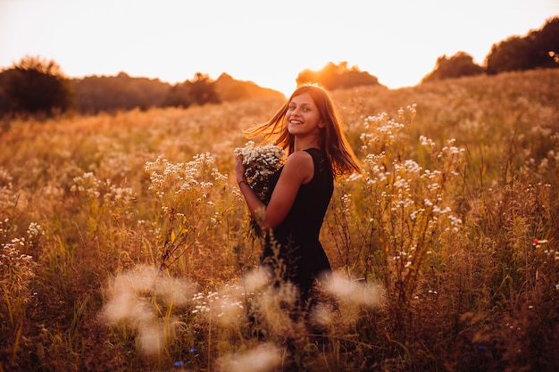 Free Photo happy woman with flowers stands on the evening field 