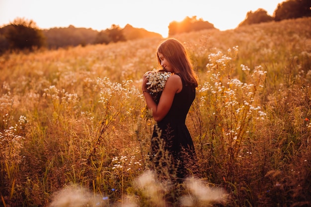 Free photo happy woman with flowers stands on the evening field