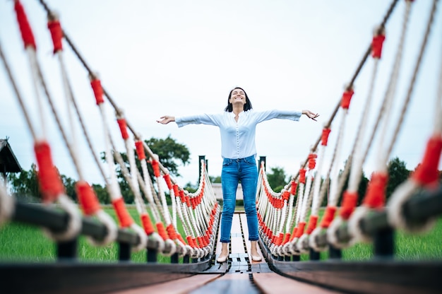 Free photo happy woman on a wooden bridge in a green meadow on a sunny day