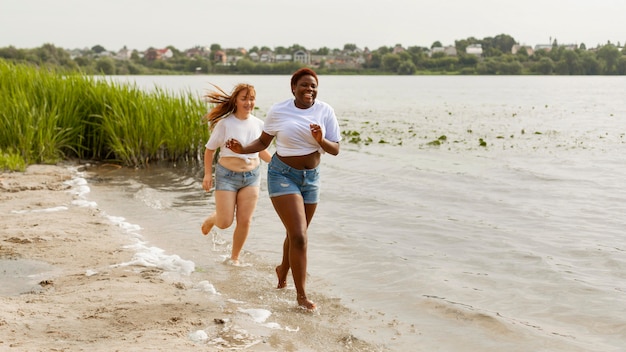 Happy women running together at the beach