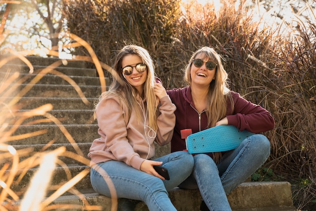 Free Photo happy women sitting in sunlight on bench