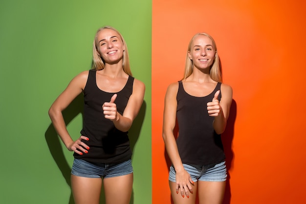 Free photo happy women standing and smiling with sign ok on studio background. beautiful female half-length portrait. young emotional women. the human emotions, facial expression concept. front view.