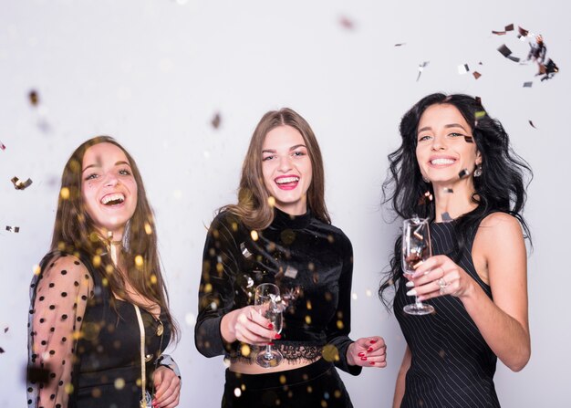 Free Photo happy women standing with champagne glasses under spangles 