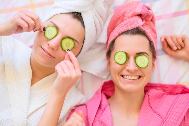 Happy women with cucumber slices on eyes