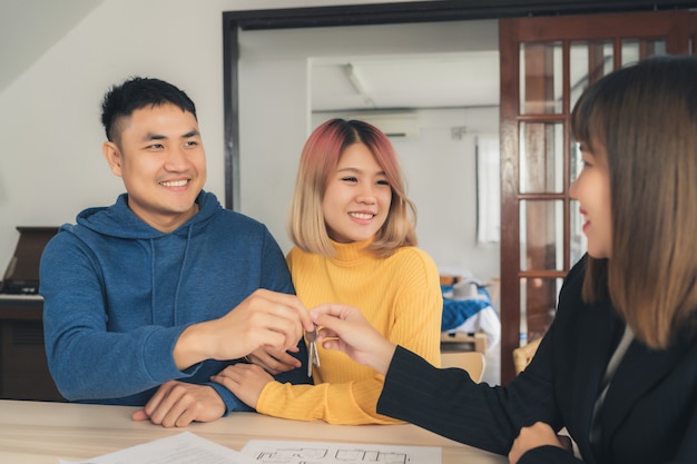 Happy young Asian couple and realtor agent