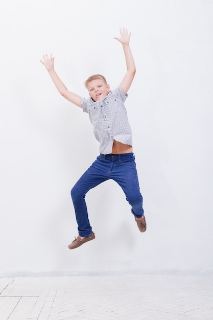 Free photo happy young boy jumping over a white background