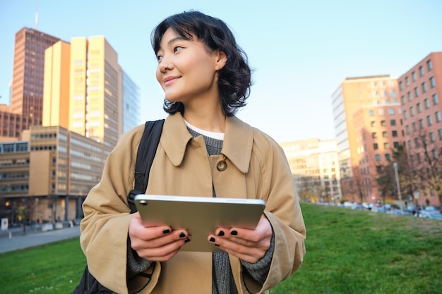 Free photo happy young brunette girl asian woman walks around city with tablet goes to university with her digi