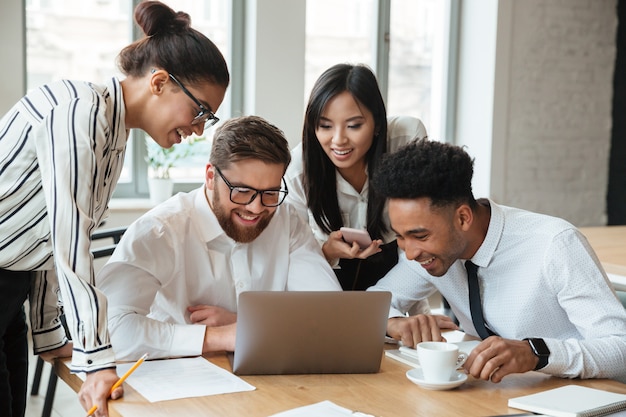 Happy young business colleagues using laptop computer.