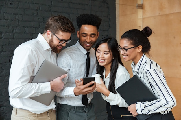 Free photo happy young business colleagues using mobile phone.