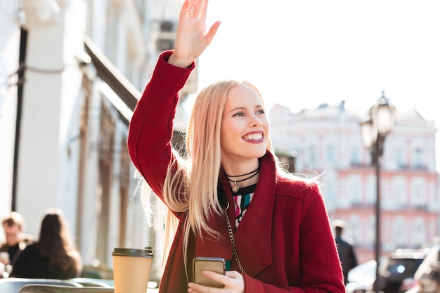 Happy young caucasian woman sitting in cafe chatting and waving