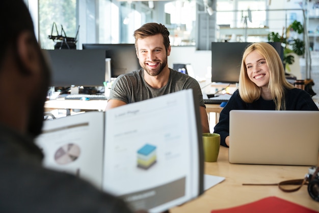 Happy young colleagues sitting in office coworking