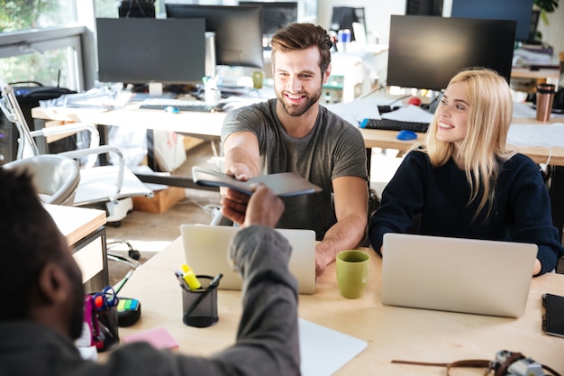 Free photo happy young colleagues sitting in office coworking