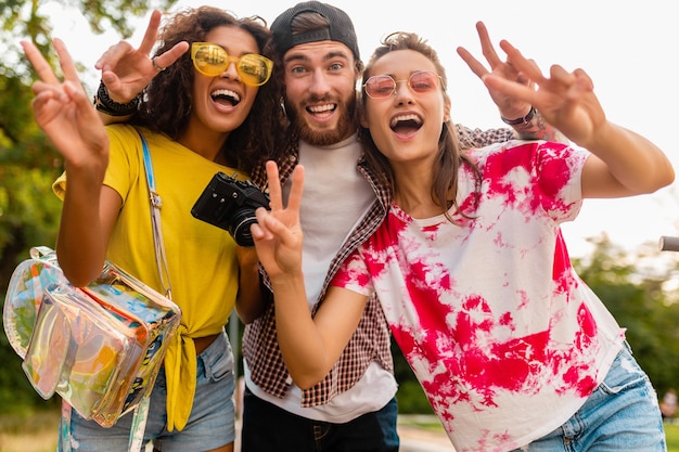 Free photo happy young company of emotional smiling friends walking in park with photo camera, man and women having fun together