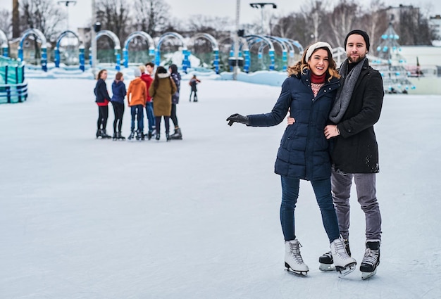 Happy young couple dating in the ice rink, hugging and enjoying winter time