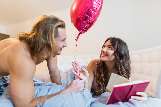 Happy young couple holding pink heart shape balloon in hands