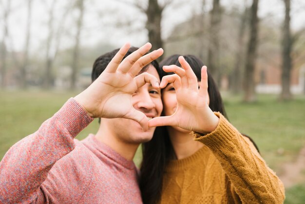 Happy young couple hugging showing heart sign