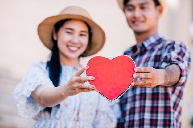 Happy young couple is holding red paper hearts