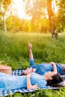 Free photo happy young couple looking at sky while lying on blanket in nature