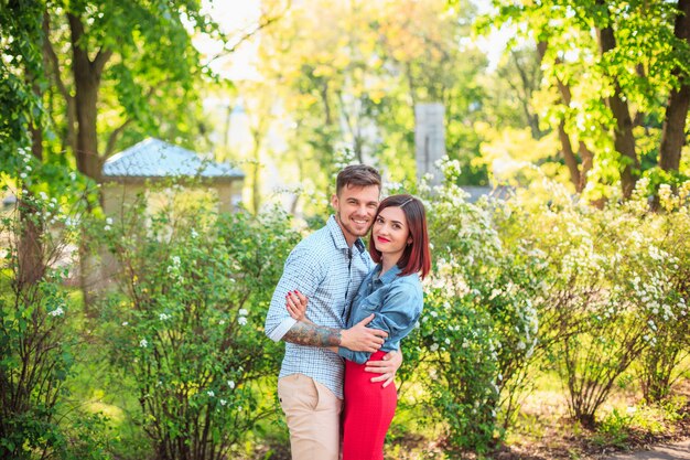 Happy young couple at park standing and laughing on the bright sunny day