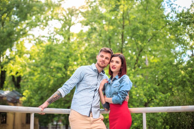 Happy young couple at park standing and laughing on the bright sunny day