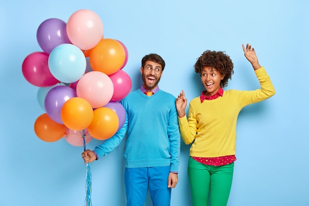 Free photo happy young couple at a party posing with balloons