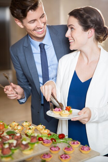 Happy Young Couple Serving Themselves in Buffet