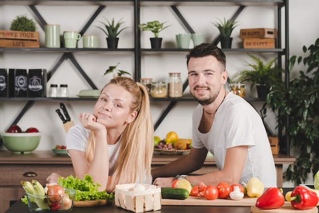 Free photo happy young couple sitting behind the kitchen counter