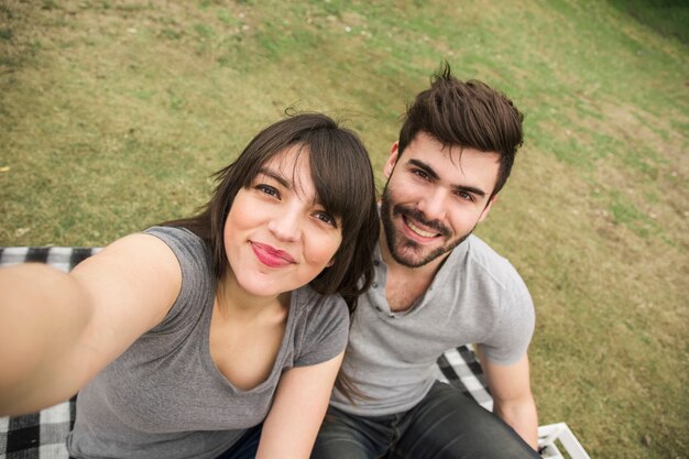 Happy young couple taking selfie in the park